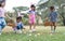 Happy group of diverse cute little children hunting Easter eggs, wearing bunny ears. kids holding basket, picking eggs on grass