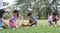 Happy group of diverse cute little children hunting Easter eggs, wearing bunny ears. kids holding basket, picking eggs on grass