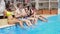 Happy group of friends enjoying summer pool party splashing and kicking their legs in the water. Pool party. Slowmotion