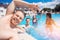 Happy group friends two guys and girls relax in turquoise pool, young man makes selfie photo, sunlights. Concept fun