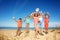 Happy group of kids jump lifting hands on the sand