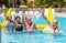 Happy group of senior people playing volleyball in the swimming pool with inflatable net and ball. Winners with happiness and