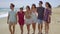 Happy group of young students walking on a beach