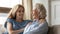 Happy grown up grandchild hugging shoulders of beloved grandmother