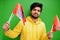 Happy Guru Nanak Jayanti concept. Young indian man in yellow sweatshirt hold flags. Cool south asian guy wear hoodie celebrating