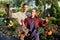 Happy guy and girl gardeners hold pots with petunia in the wonderful garden on a sunny day.