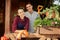 Happy guy and girl gardeners standing on the wooden veranda with plants on a sunny day