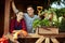 Happy guy and girl gardeners standing on the wooden veranda with plants on a sunny day