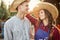 Happy guy and girl gardeners in a straw hats look at each other in the garden on a sunny day.