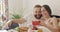 Happy guy and girl watching funny video and laughing in bed. Young romantic family having breakfast and talking while