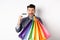 Happy guy shopaholic holding colorful shopping bags and showing plastic credit card, smiling excited, standing white