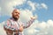 Happy hairless man with beard pointing to cloudy beautiful sky.