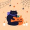 Happy Halloween. A fat cute black cat clutched at the pumpkin with its claws. Cartoon character of animal holidays