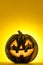 Happy Halloween. Funny glowing pumpkin Jack-o-lantern on a yellow background.