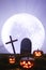 Happy Halloween. Glowing Jack-o-lanterns, cross and gravestone against the backdrop of a large full moon. 3D rendering