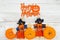 Happy Halloween greeting with orange pumpkins with fall scarecrows on weathered wood