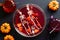 Happy Halloween holiday concept. Halloween decorations, bowl of bloody color drink, skeletons, pumpkins on black background. Flat