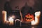 Happy Halloween. Jack o lantern pumpkin with candles, bowl, witch broom and bats, ghosts on background in dark spooky room. fall