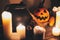 Happy Halloween. Jack o lantern pumpkin with candles, bowl, witch broom and bats, ghosts on background in dark spooky room. fall