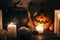 Happy Halloween. Jack o lantern pumpkin with candles, bowl, witch broom and bats, ghosts on background in dark spooky room. fall