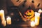 Happy Halloween. Jack o lantern pumpkin with candles, bowl, witch broom and bats, ghosts on background in dark spooky room. fall