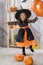 Happy Halloween. A little beautiful girl in a witch costume celebrates a home in an interior