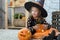 Happy Halloween. A little beautiful girl in a witch costume celebrates a home in an interior