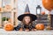 Happy Halloween. A little beautiful girl in a witch costume celebrates a home in an interior