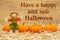 Happy Halloween message with scarecrow and orange pumpkins on straw hay