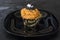 Happy Halloween orange and black decorated cupcake with a black witch hat and butter cream with beads on a black plate