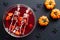 Happy Halloween party composition. Flat lay, top view bowl of bloody color drink, pumpkins, spiders on black background