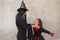 Happy halloween. Pretty young woman and girl dressed as witches on grey background play with terrifying and strangling gestures