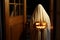 Happy Halloween! Scary ghost with glowing Jack o lantern at doors in spooky atmospheric night. Person dressed as ghost trick or