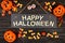 Happy Halloween sign and frame of candy on black wood