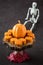 Happy Halloween, small pumpkin cakes, orange ceramic pumpkin on a wooden cake stand, plastic skeleton, red maple leaves