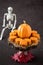 Happy Halloween, small pumpkin cakes, orange ceramic pumpkin on a wooden cake stand, plastic skeleton, red maple leaves