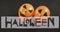 Happy halloween text banner over two halloween pumpkin printed balloons against black background