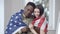 Happy handsome African American man and Caucasian woman posing with US flag hugging and smiling looking at camera