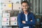 Happy handsome asian business entrepreneur smiling and standing in front of stock product shelf in his home.