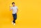 Happy handsome Asian shopaholic man showing credit card in hand isolated on yellow background