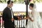 Happy handsome groom and beautiful bride in white dress in wedding arbor at ceremony