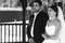 Happy handsome groom and beautiful bride in white dress in wedding arbor at ceremony b&w