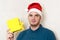 Happy handsome guy in santa hat holds a box with gift in his hand. young brutal man receives and gives a present. holiday concept.