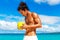 Happy handsome man of Asian appearance with coconut on the tropical beach on sunny summer day during holidays vacation. Tropical