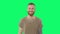 Happy handsome man on chroma key. Positive bearded tattooed hipster is looking to the camera and smiling on green screen