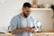 Happy handsome man reading good news on smartphone in kitchen.