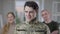 Happy handsome military recruit looking at camera smiling with blurred father and mother standing at background