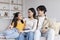 Happy handsome millennial asian couple watching at teen daughter, hugging, sitting on sofa in living room