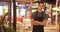 Happy handsome young Latino waiter standing in outdoor patio of restaurant smiling