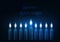 Happy hanukkah greeting card template with nine glowing burning candles on dark blue background